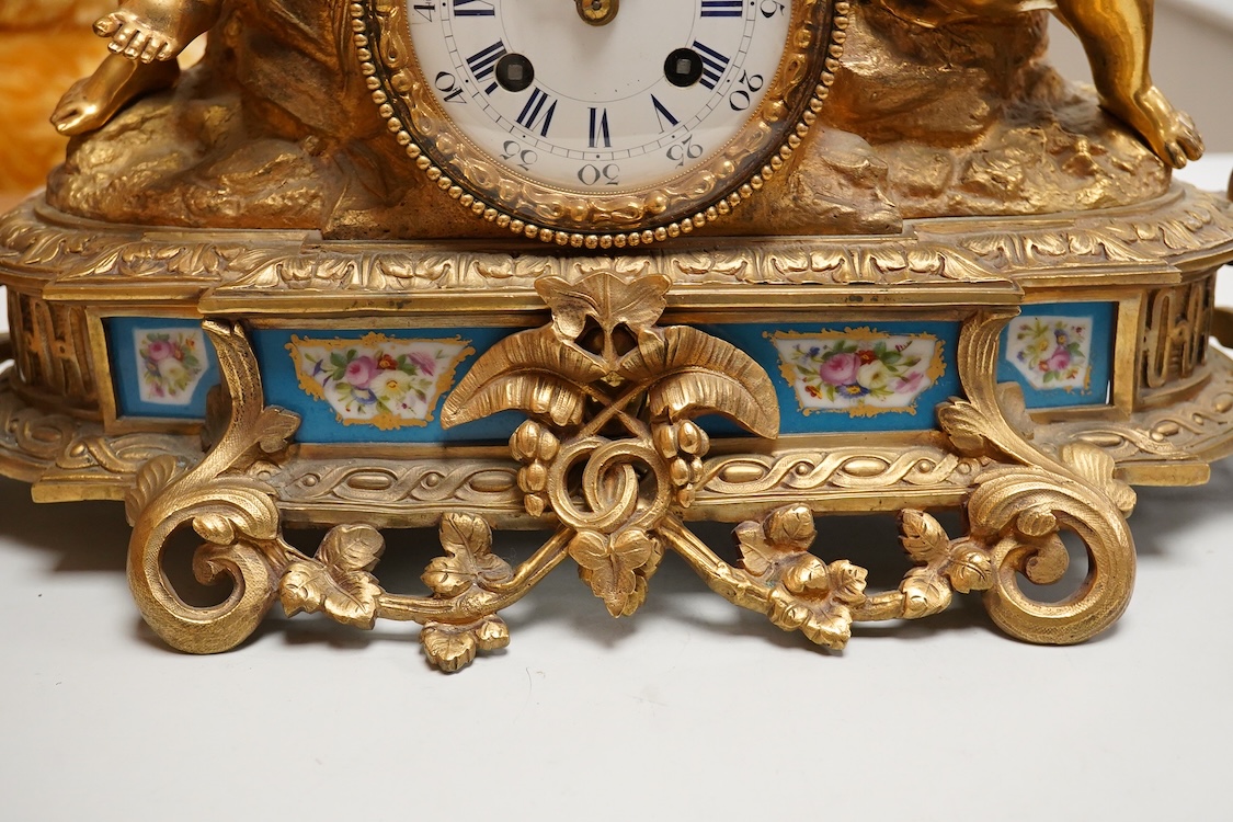 A Louis XV style figural brass mantel clock striking on a bell, with enamel dial and inset plaques, surmounted with two figures, with pendulum, no key, 42cm wide